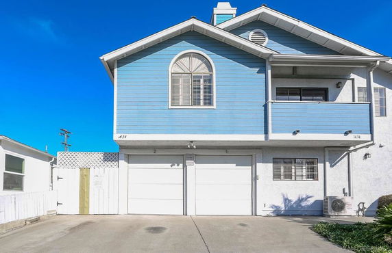 Front view of a two-story house with blue siding and an arched window above the garage.