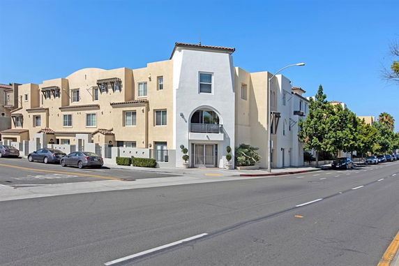 Front view of a multi-story residential building with balconies and a street in front.