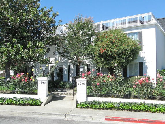 Front view of a two-story house with a balcony and garden.