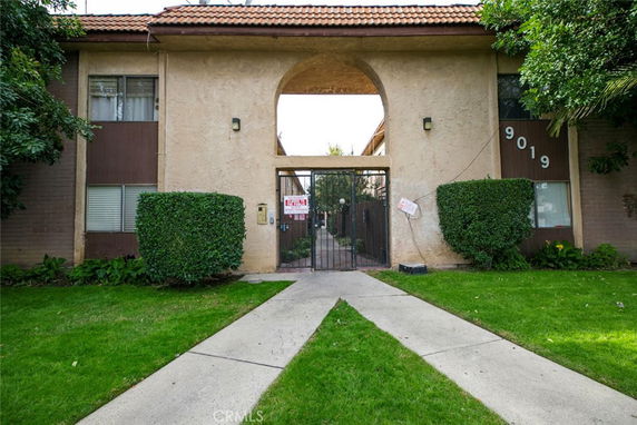 Front view of a multi-story building with arched entrance and gated courtyard.