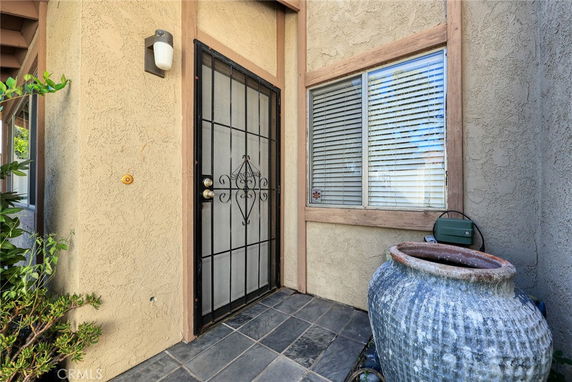 Front view of a house entrance with a metal security door and a window with blinds.