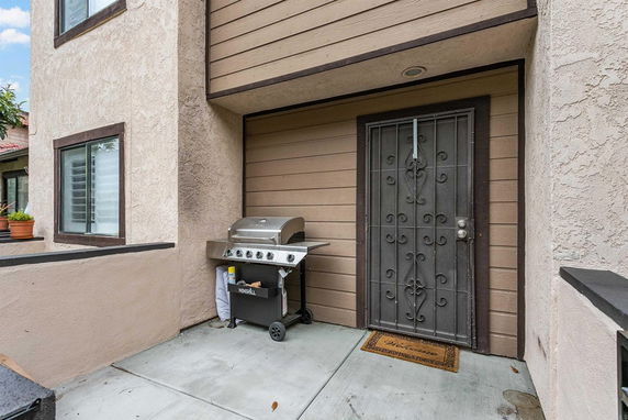 Front view of a building entrance with a metal grill door and adjacent outdoor grill.