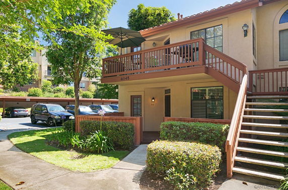 Front view of a two-story house with an outdoor staircase and wooden railing.
