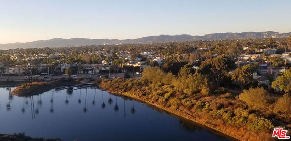 Panoramic view of residential area with hills and water body in the background.