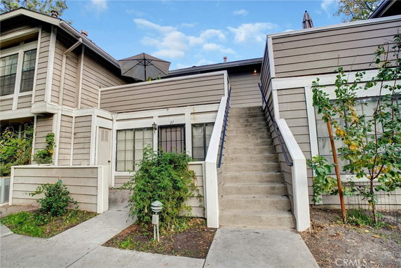 Front view of a residential building with external staircase and plants.