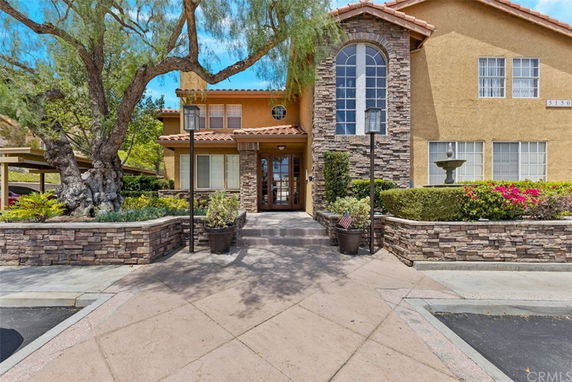 Front view of a two-story house with stone accents and large windows.