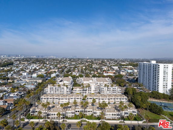 Aerial panoramic view of an urban area with multiple residential buildings and a cityscape in the background.
