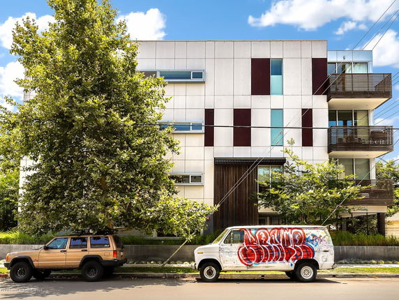 Front view of a modern multi-story building with balconies and a geometric facade.
