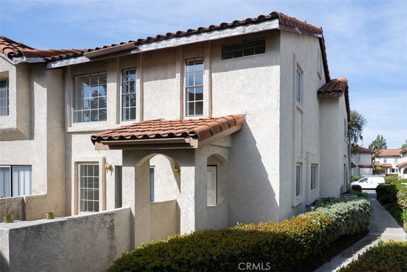 Front view of a two-story house with a red tiled roof and stucco exterior.
