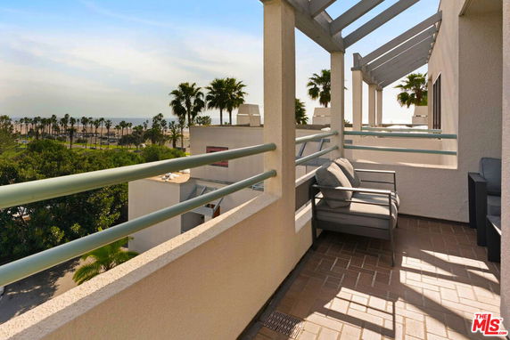 View from a building balcony showing distant ocean and palm trees.