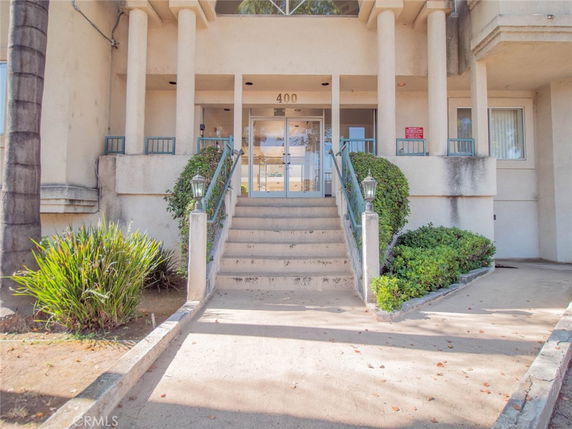 Front view of a building entrance with stairs leading up to glass doors.