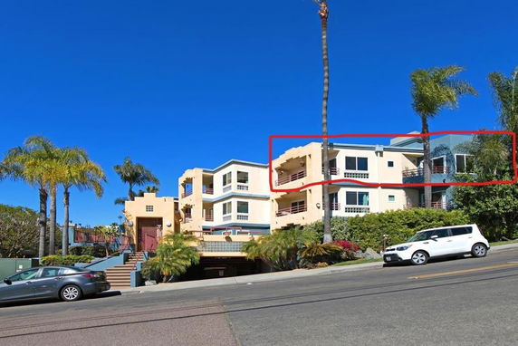 Front view of a multi-story residential building with balconies and a garage.