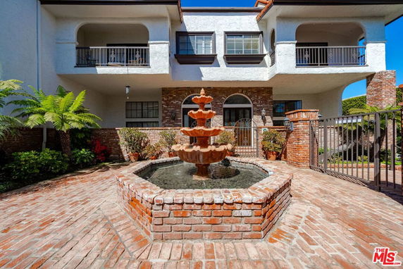 Front view of a two-story house with a fountain and brick exterior.