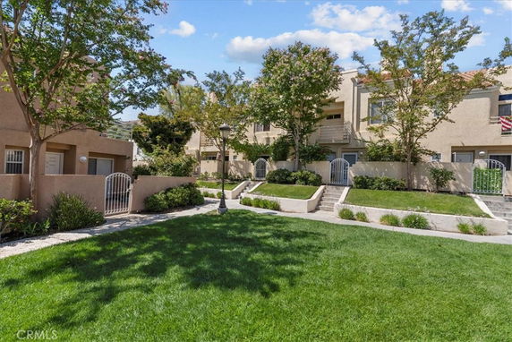 Front view of a multi-story residential building with balconies and a landscaped garden.