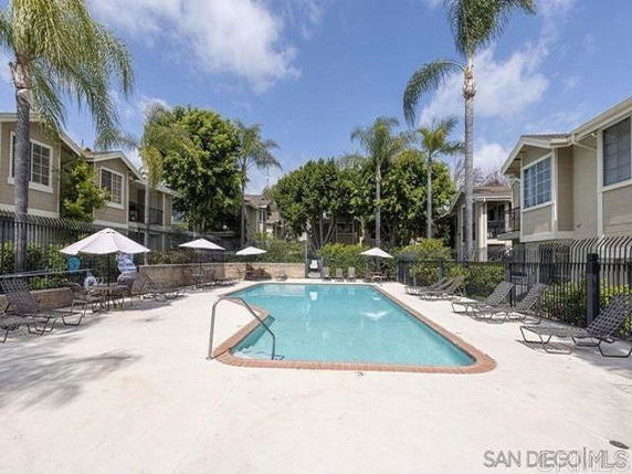 Outdoor swimming pool area with sun loungers and umbrellas.
