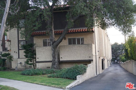 Front view of a multi-story building with a beige exterior and tile roof accents.