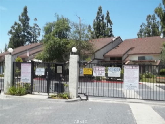 Front view of a gated residential building with multiple levels and a pitched roof.