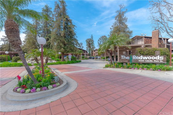 Front view of a residential complex with a sign that reads 'The Redwoods.'