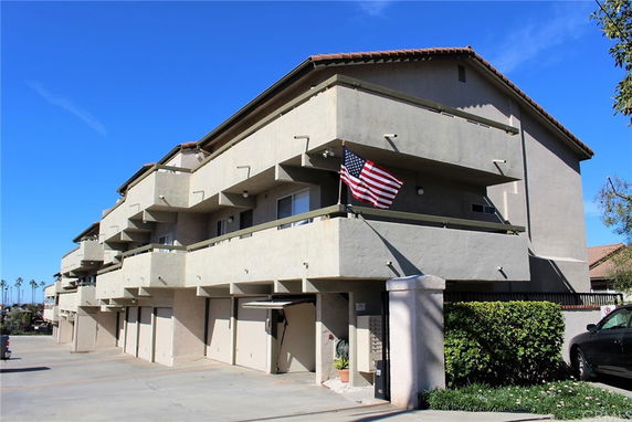 Front view of a multi-story building with balconies and a flag.