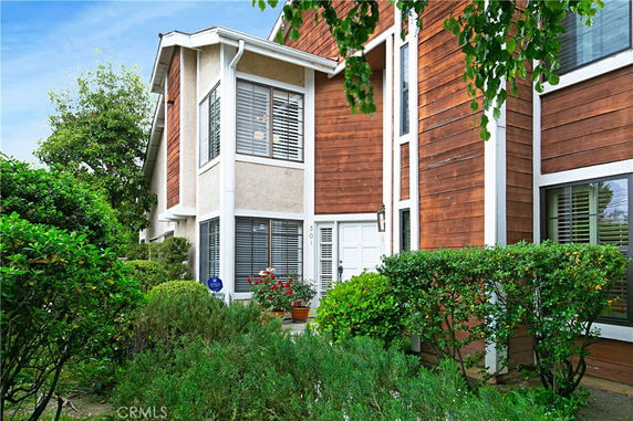 Front view of a two-story house with wooden exterior and large windows.