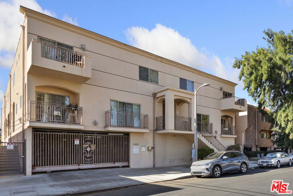 Front view of a multi-story residential building with balconies and a gated entrance.