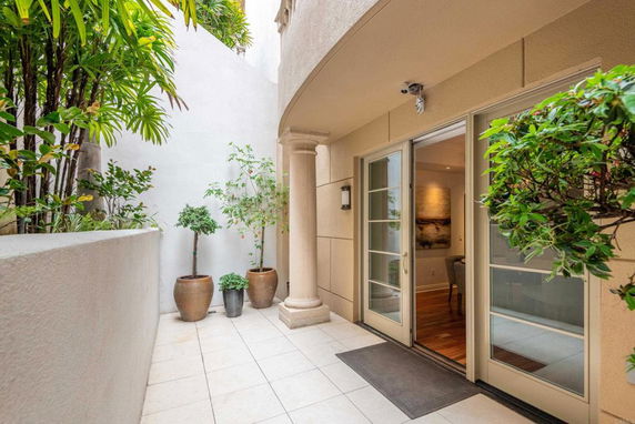 Exterior view of a building with a small patio area and potted plants.