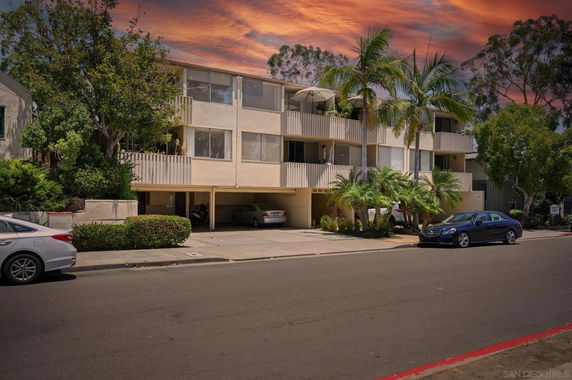 Front view of a multi-story residential building with covered parking area.