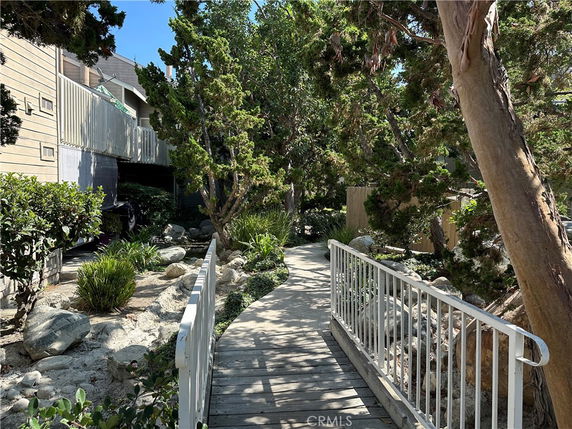 Pathway surrounded by rocks and trees with a view of building exterior.