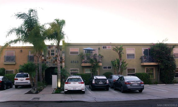 Front view of a two-story apartment building with parking spaces in front.