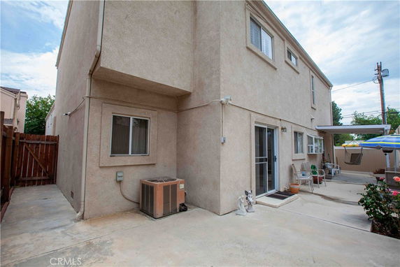 Side view of a two-story house with a patio area and sliding glass door.