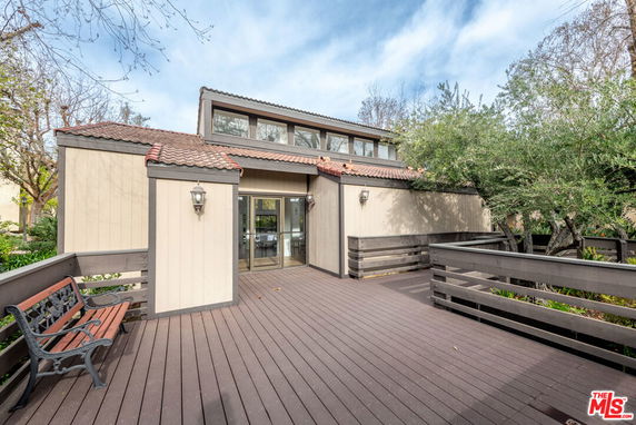 Front view of a contemporary house with a wooden deck and large windows.