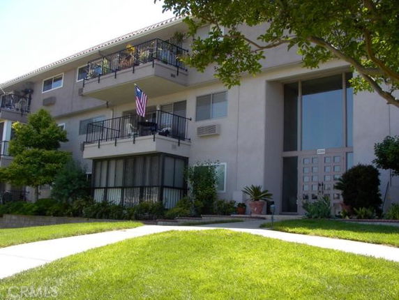 Front view of a multi-story apartment building with balconies and a glass entrance.