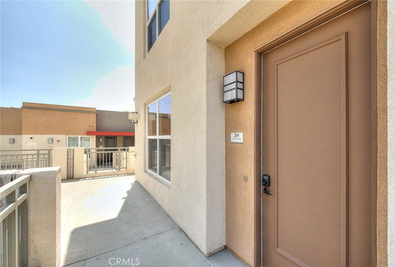 Front view of an apartment entrance with a balcony and modern exterior lighting.