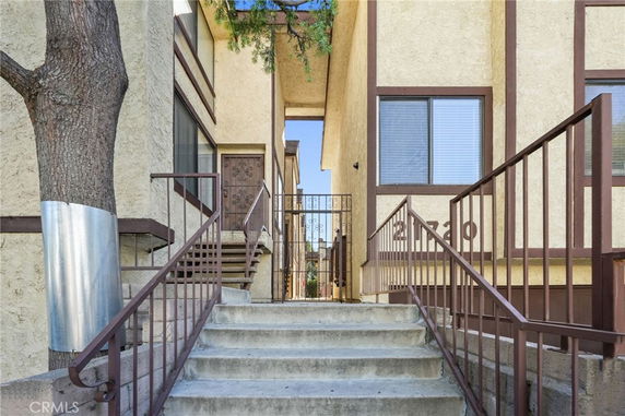 Entrance view of a multi-unit residential building with a stairway and metal railings.