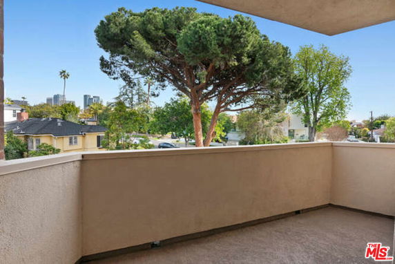 Balcony view showing surrounding area with trees and houses.