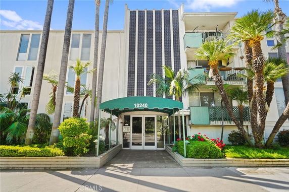 Front view of a multi-story building with a green entrance canopy and balconies.