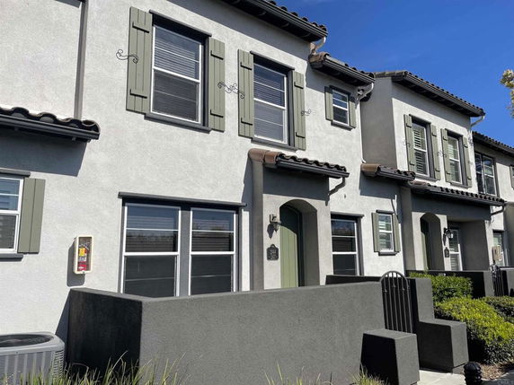 Front view of a two-story townhouse with shutters and a small front patio.