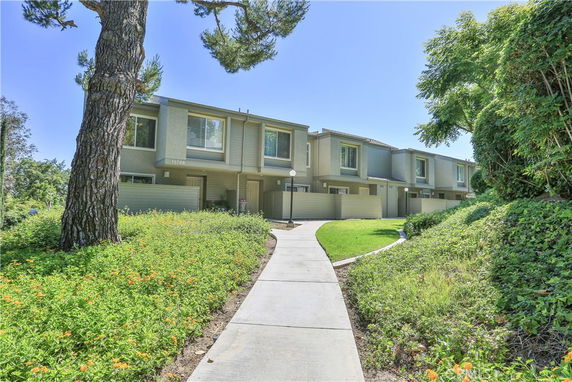 Front view of a row of two-story townhouses with a walkway leading up to them.