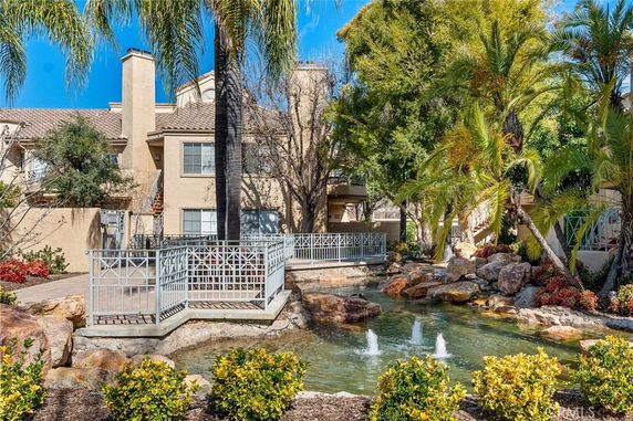 Front view of a residential building with a small bridge over a water feature.