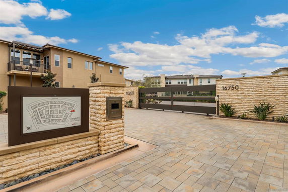 Front view of a modern building with a gated entrance and a stone facade featuring a street address.