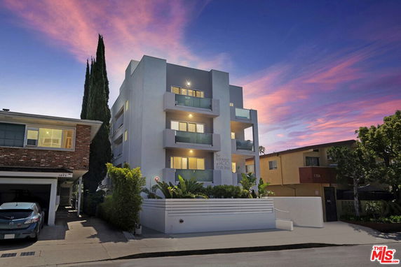 Front view of a modern multi-story apartment building with balconies, captured during sunset.