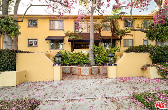 Front view of a two-story apartment building with yellow exterior and multiple windows.