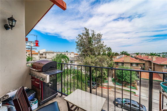Panoramic view from a balcony showing surrounding residential area with rooftops and trees.