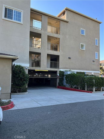 Front view of a multi-story residential building with balconies and parking entrance.