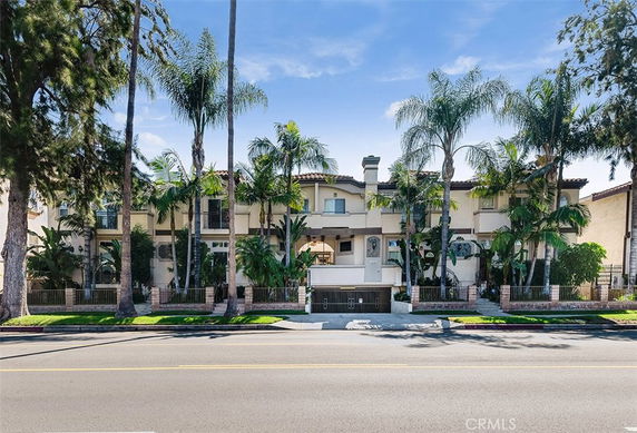 Front view of a multi-story residential building with palm trees.