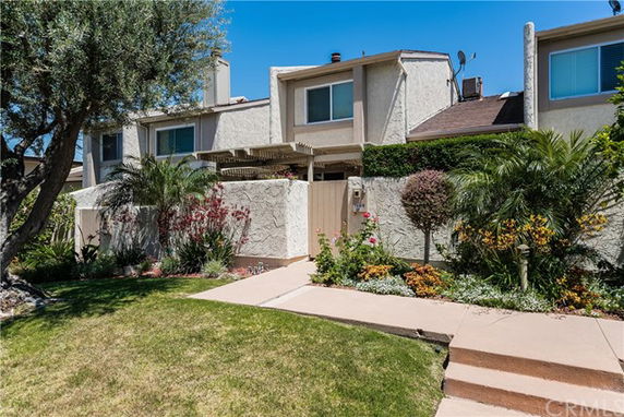 Front view of a two-story house with a flat roof and a small garden.