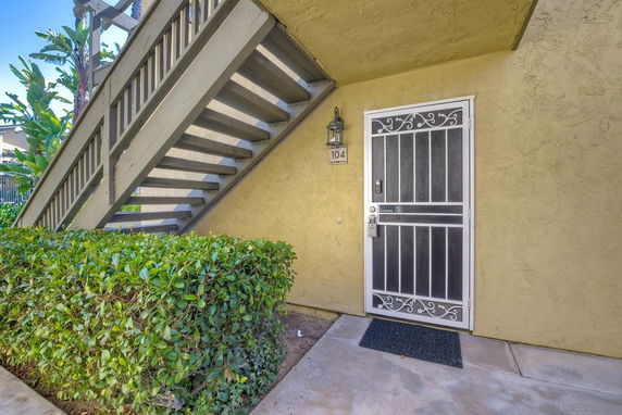 Entrance of a building with a metal screen door and exterior stairs.