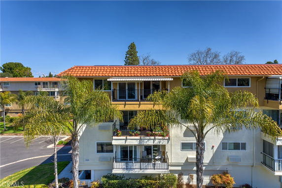 Front view of a multi-story building with balconies and red-tiled roof.