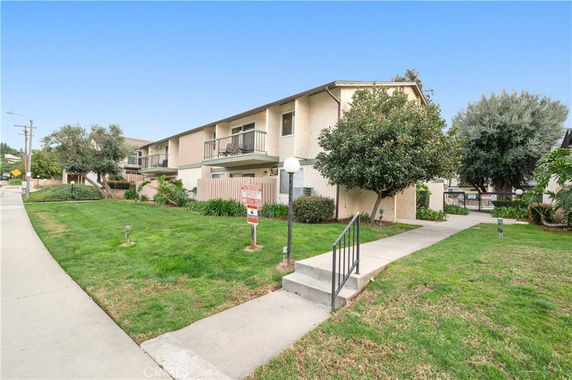 Front view of a two-story residential building with balconies and a walkway leading to the entrance.