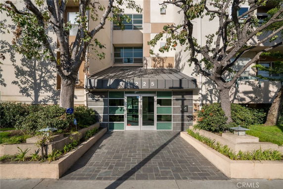 Front view of a multi-story residential building entrance with a modern glass door and pathway.